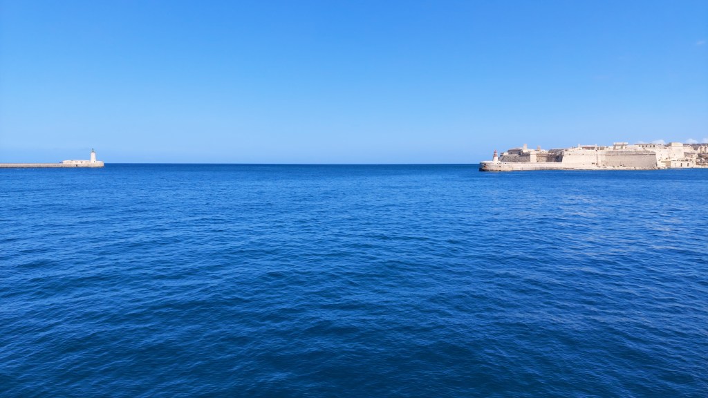 A beautiful panoramic view with St. Elmo Lighthouse on the left and Ricasoli East Breakwater on the right, Valletta, Malta.
